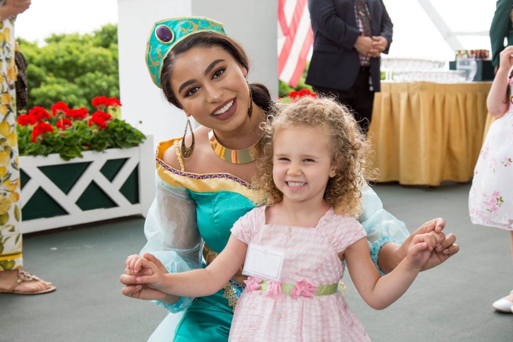 Princess Jasmine holds hands with a 3-year-old girl for a photo